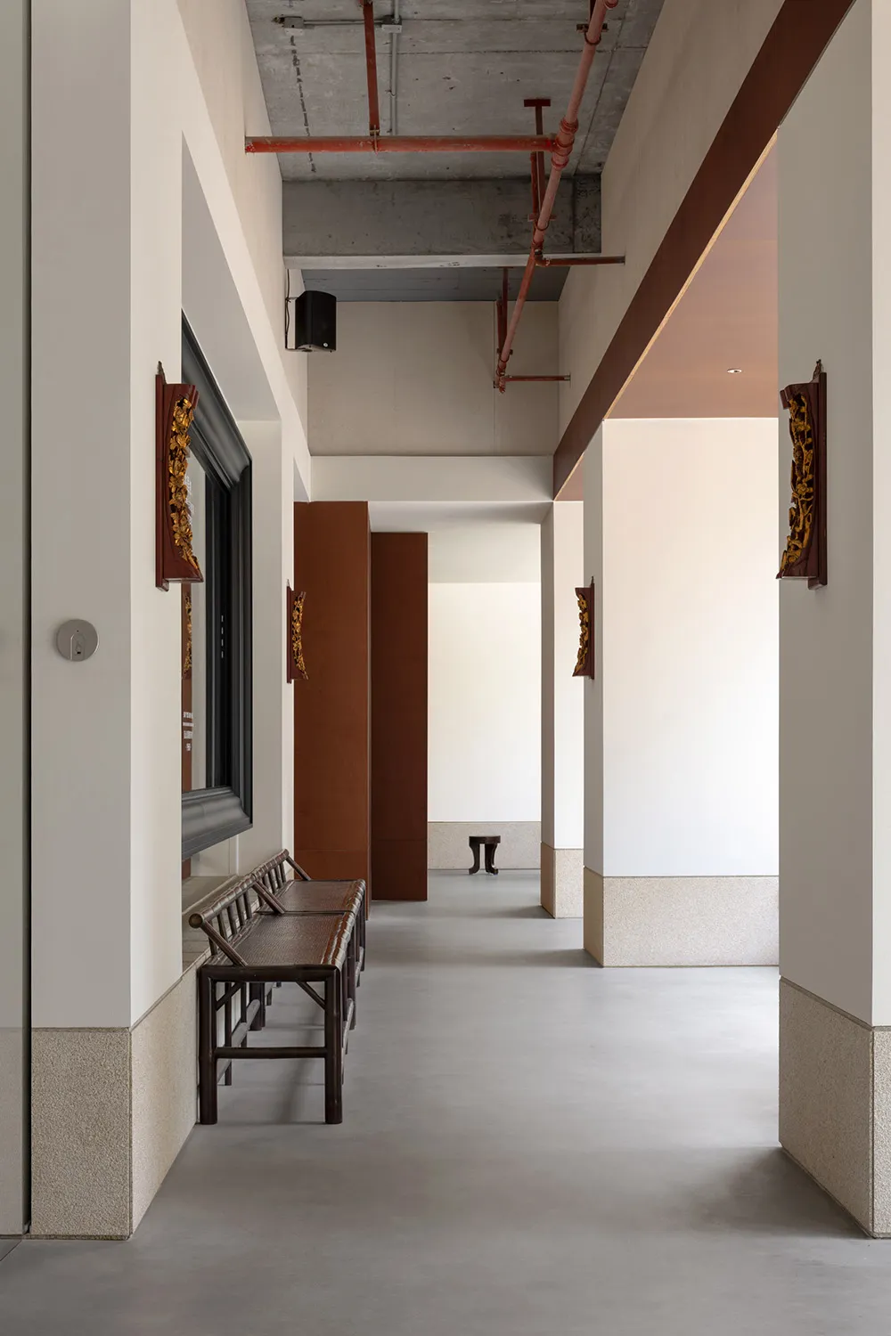 A minimalist corridor with concrete walls, benches, and wooden accents.