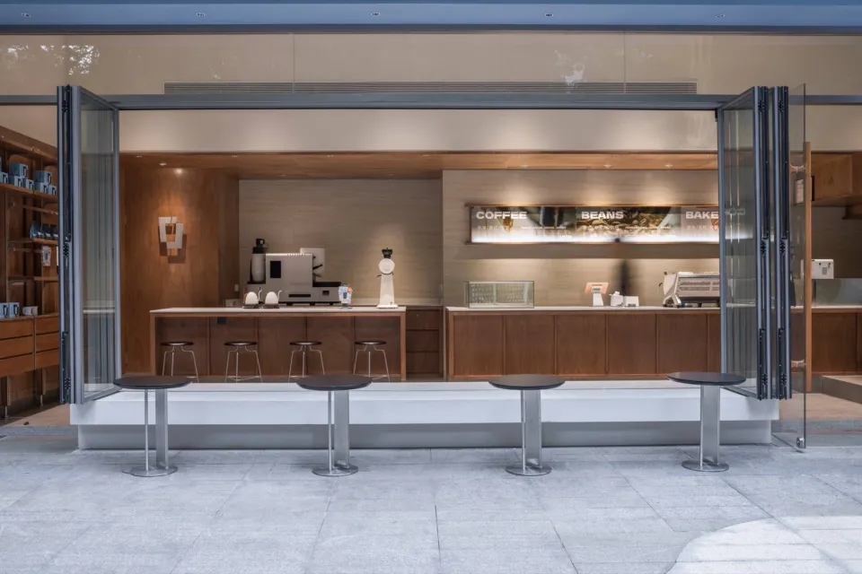 A modern coffee shop with a wooden counter and glass folding doors.