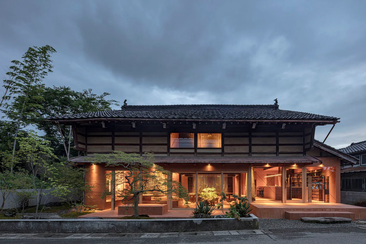 A modern house with a zinc roof and wooden terrace in a residential setting.