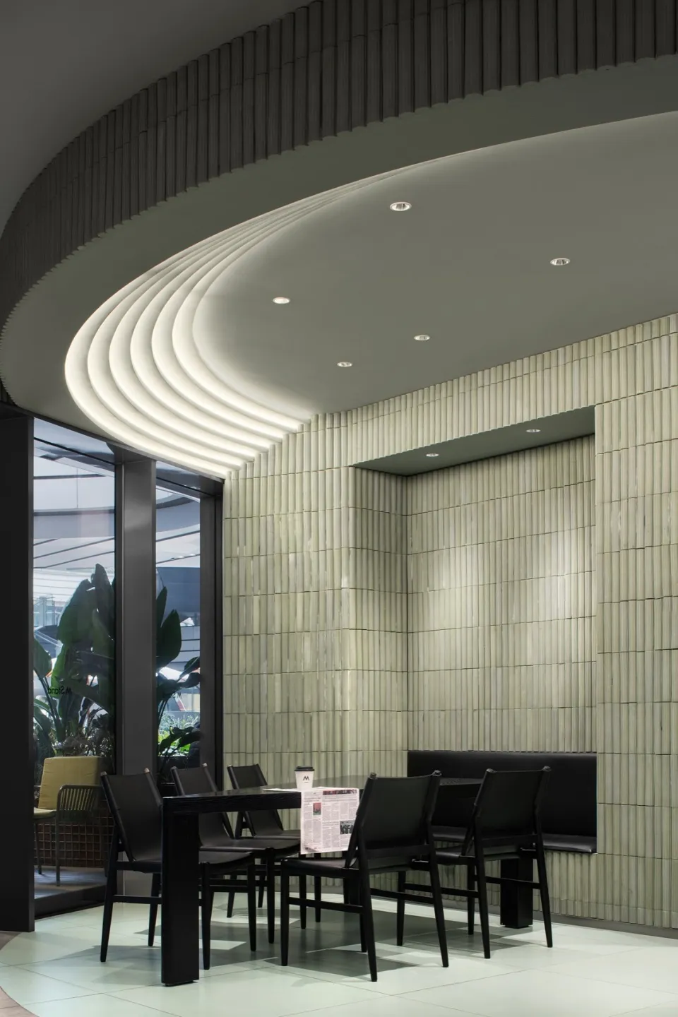Modern restaurant interior with white tile walls and black furniture, featuring a cozy seating area and elegant design.