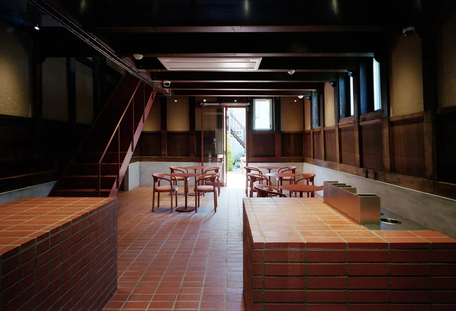 Modern cafe interior with brick walls, concrete flooring, and wooden furniture.