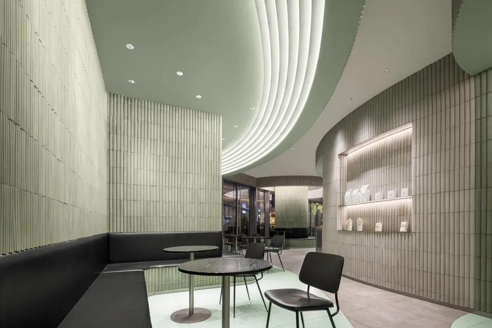 Contemporary restaurant interior with textured concrete walls and ceiling, modern furniture, and sophisticated lighting.