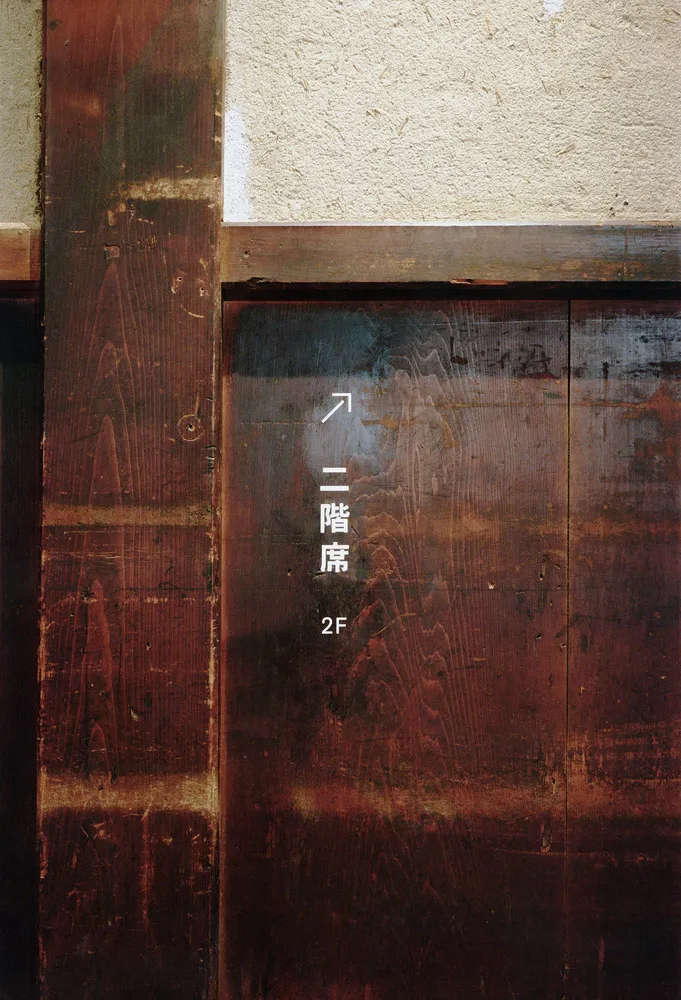 A wooden sign with Japanese text and an upward-pointing arrow.
