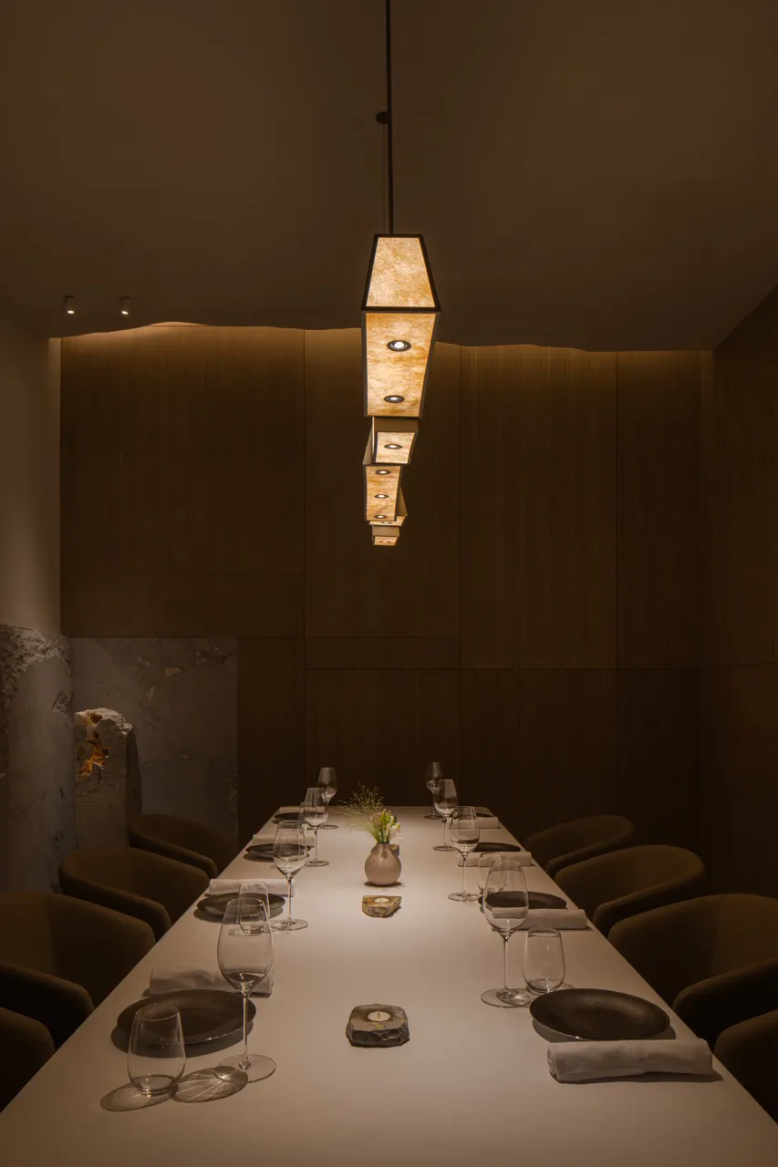 A modern restaurant dining room with wooden floors and hanging lights.