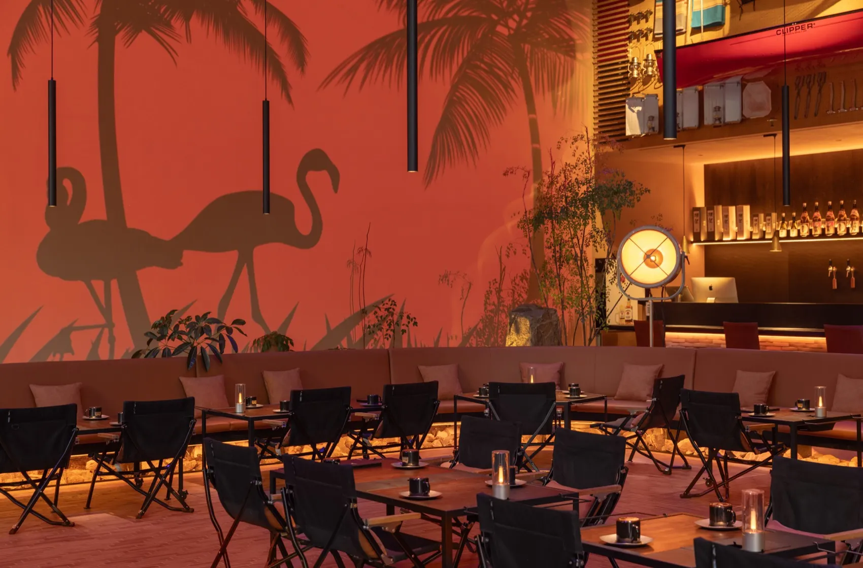 A modern restaurant bar with metal tables, wooden chairs, and glass decor.
