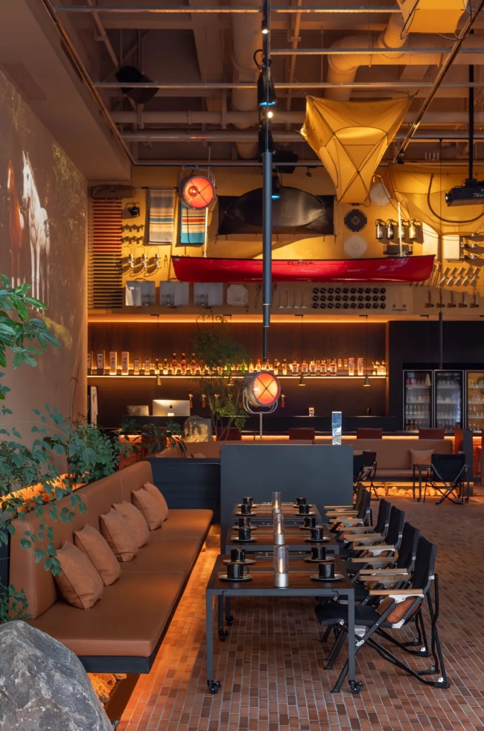 A modern industrial restaurant interior with exposed brick walls, wooden tables, and hanging lights.