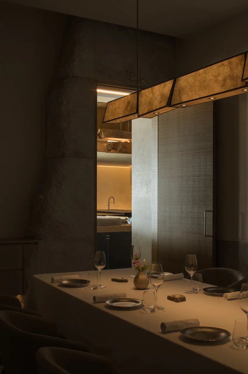 Modern restaurant interior with wooden floors and concrete walls, featuring a dining table set for a meal.