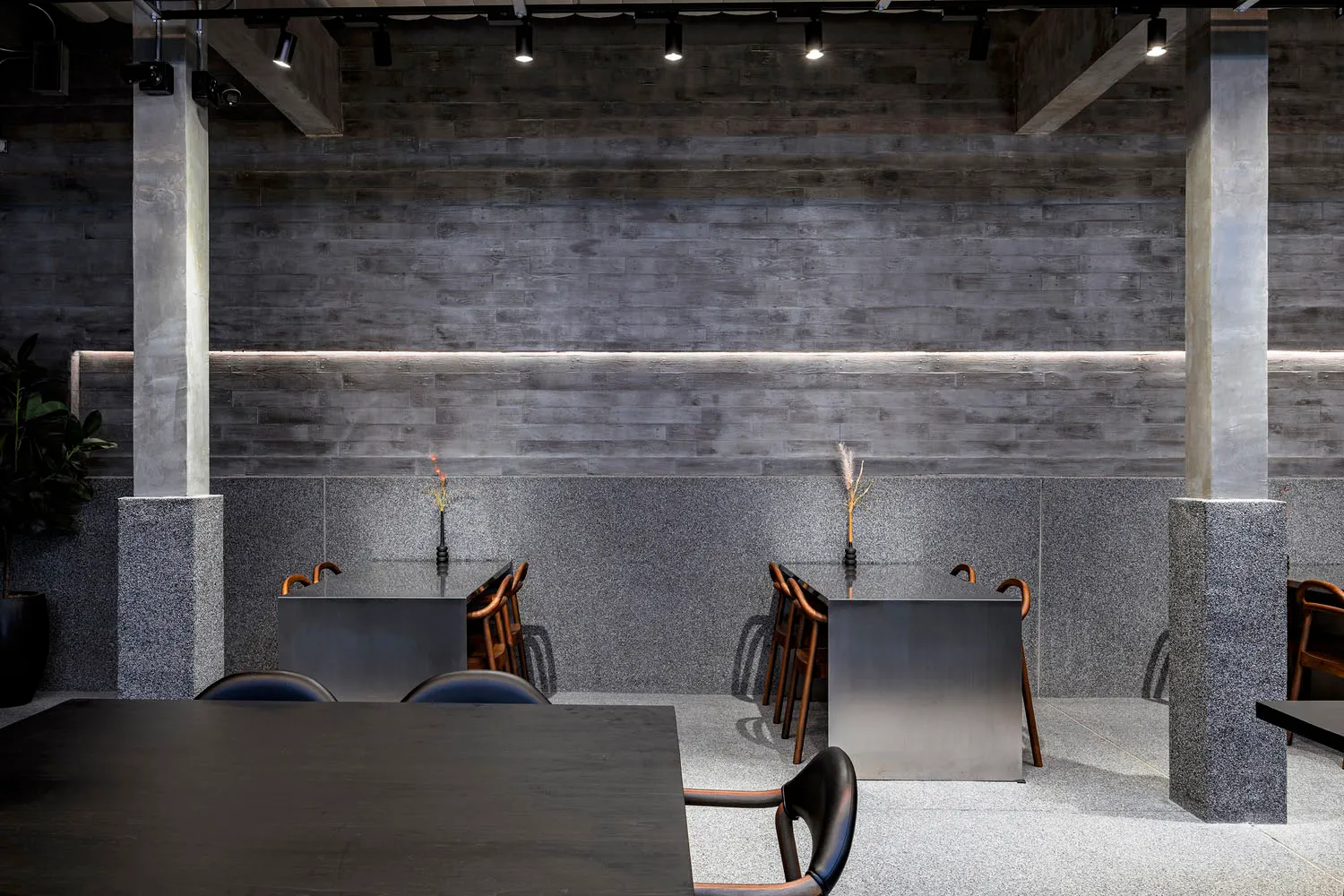 Modern restaurant interior with industrial design elements, featuring concrete, granite, and metal materials.