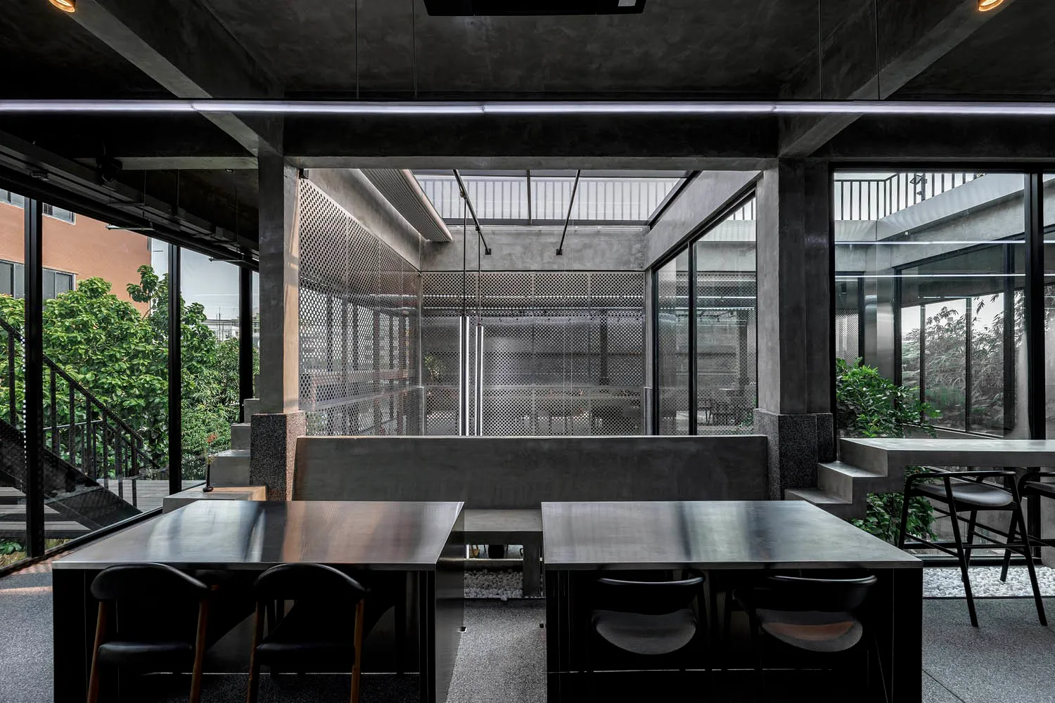 A minimalist office space with concrete walls, tables, and chairs.