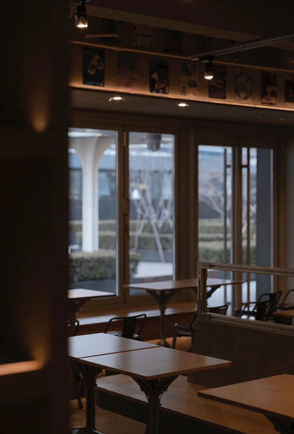 Indoor restaurant interior with wooden tables and chairs, industrial design elements, and natural light.