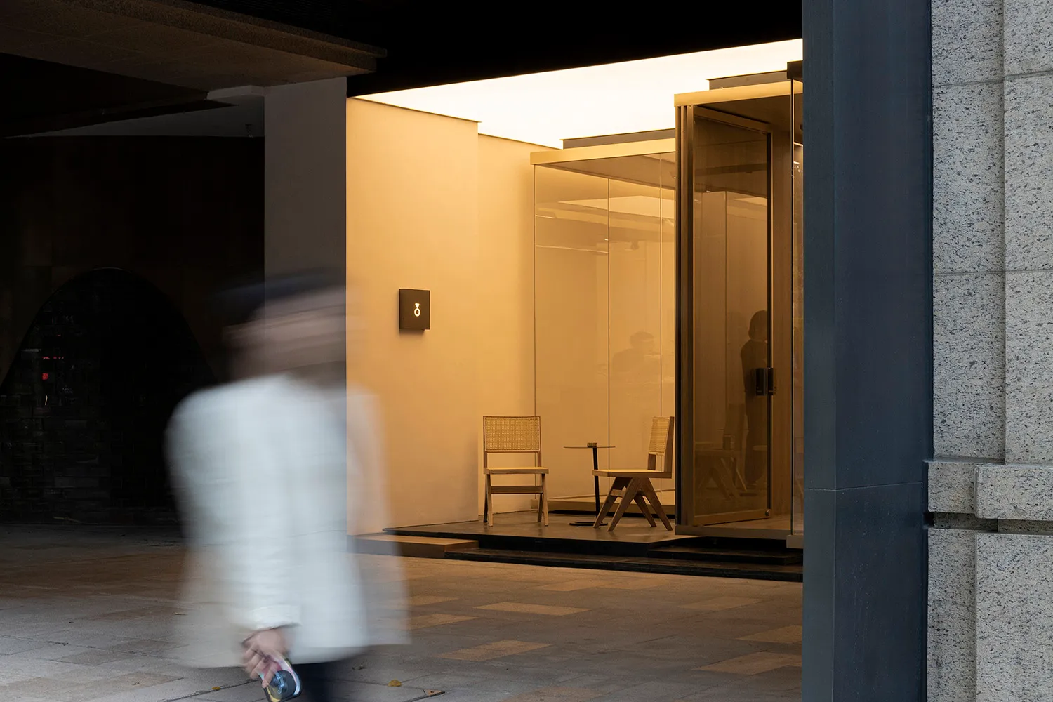 A minimalist retail storefront featuring glass walls and furniture.