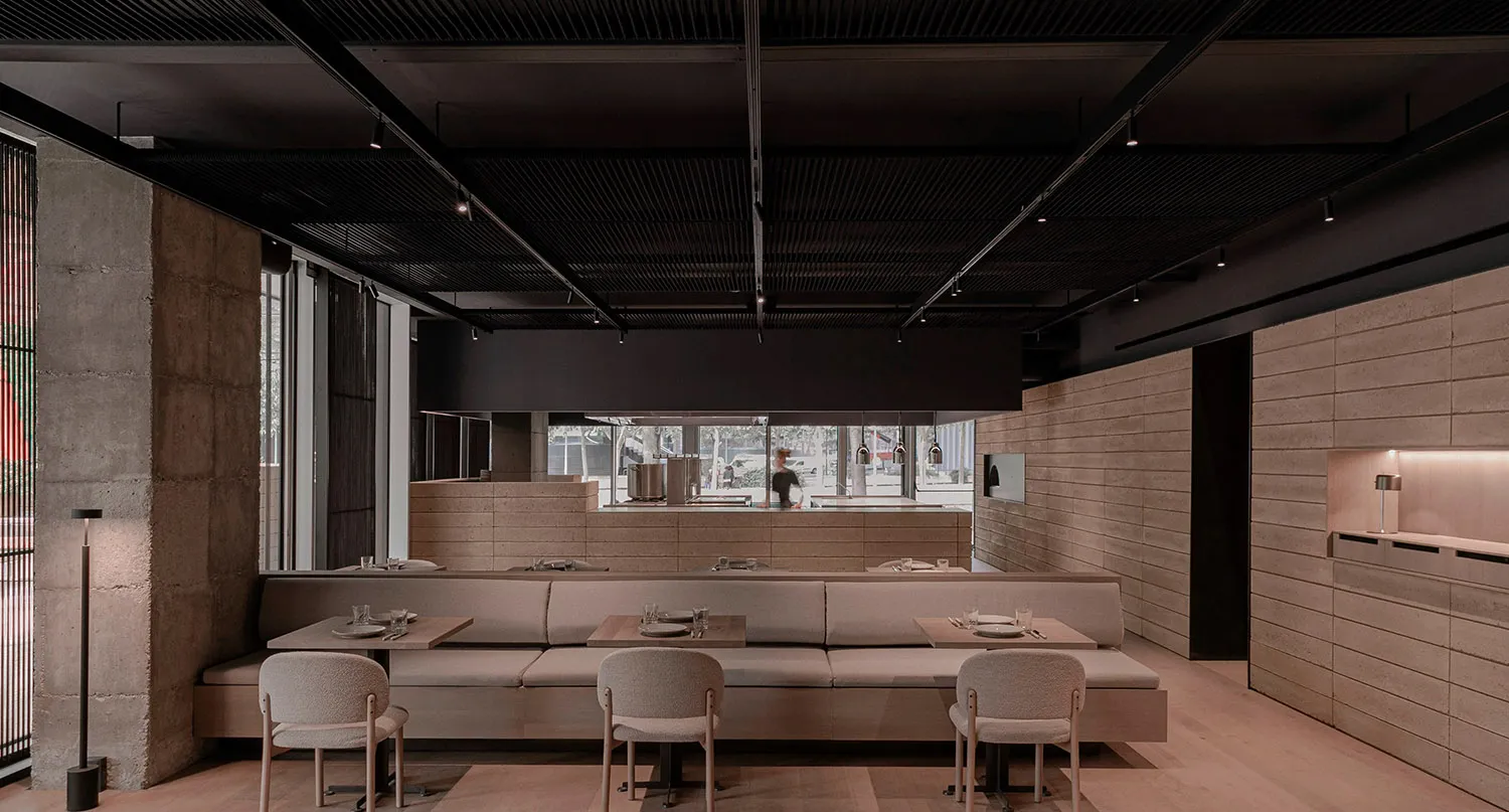 Modern industrial restaurant interior with furniture, concrete, and stone elements.