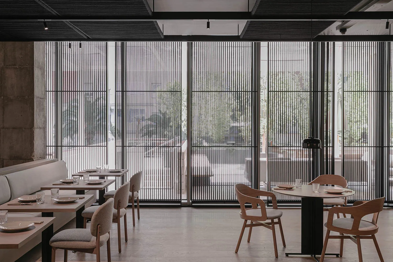 Modern restaurant interior with concrete and wooden elements, featuring contemporary design and comfortable seating arrangeme