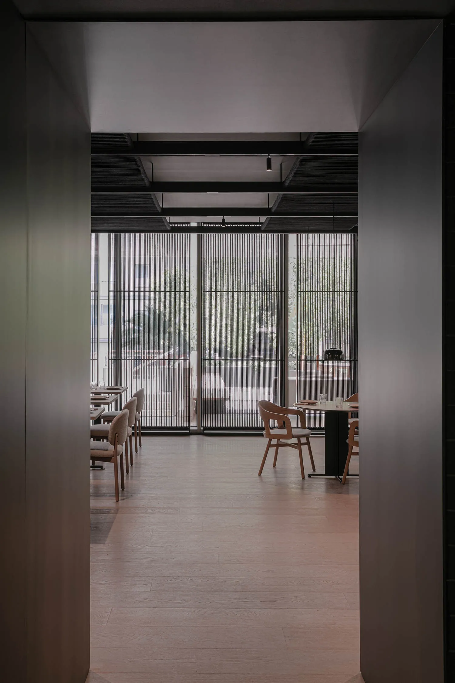 Modern restaurant interior with wooden seating, metal railings, and glass partitions