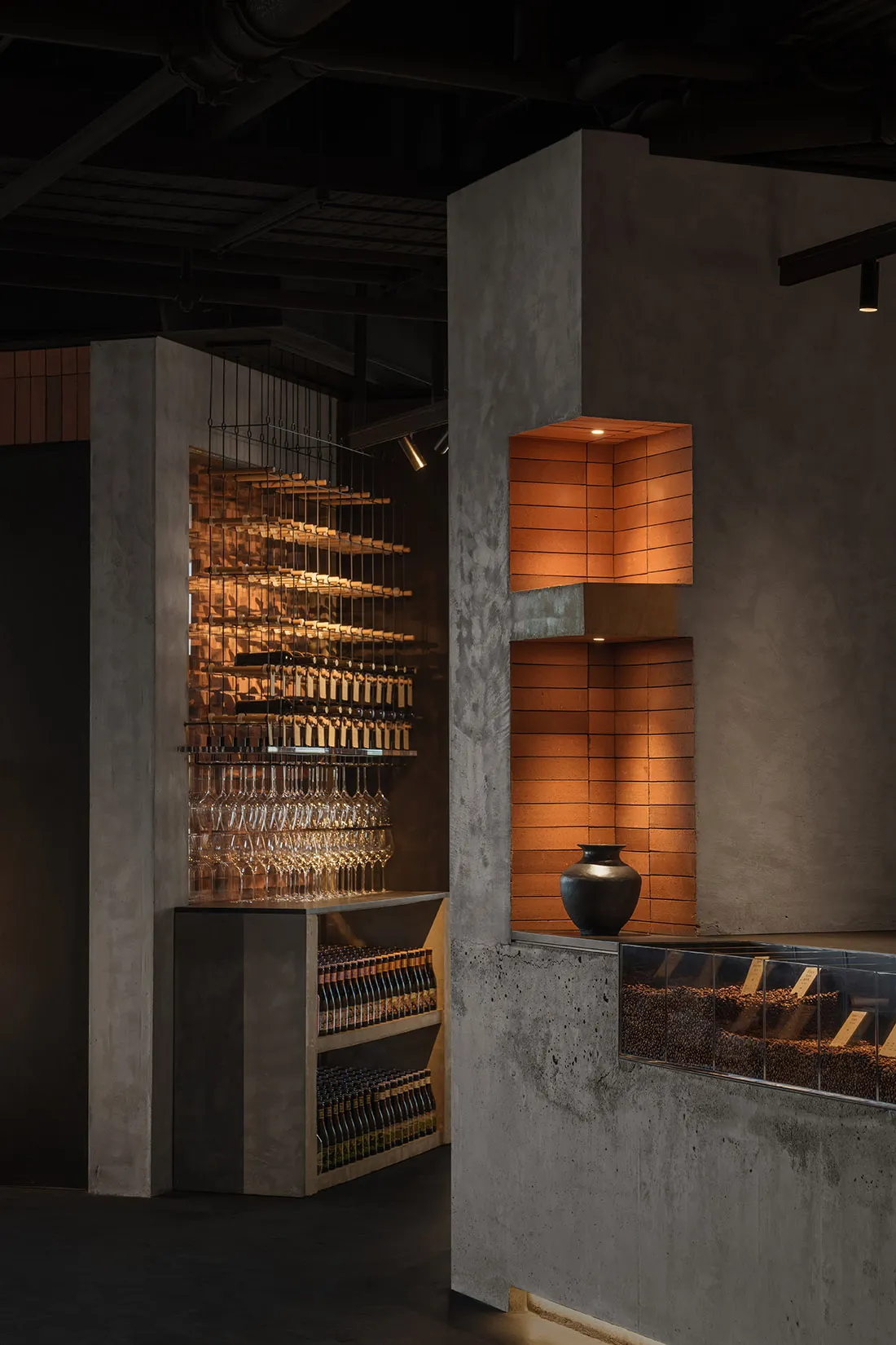 Industrial design restaurant interior with concrete shelves and illuminated brick wall feature.