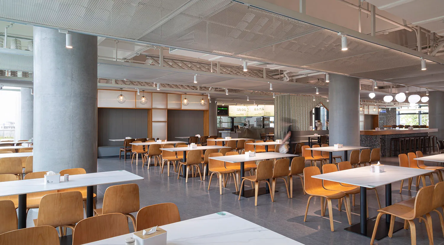 現代簡約風格餐廳室內，搭配混凝土與木質元素，並設有充足座位。