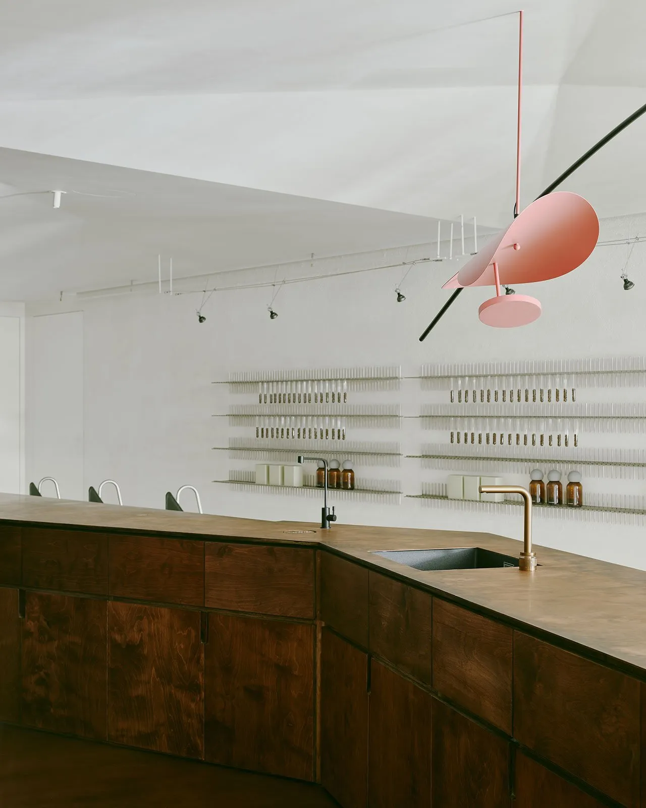 Modern commercial kitchen with minimalist design, featuring a wooden counter and shelving.