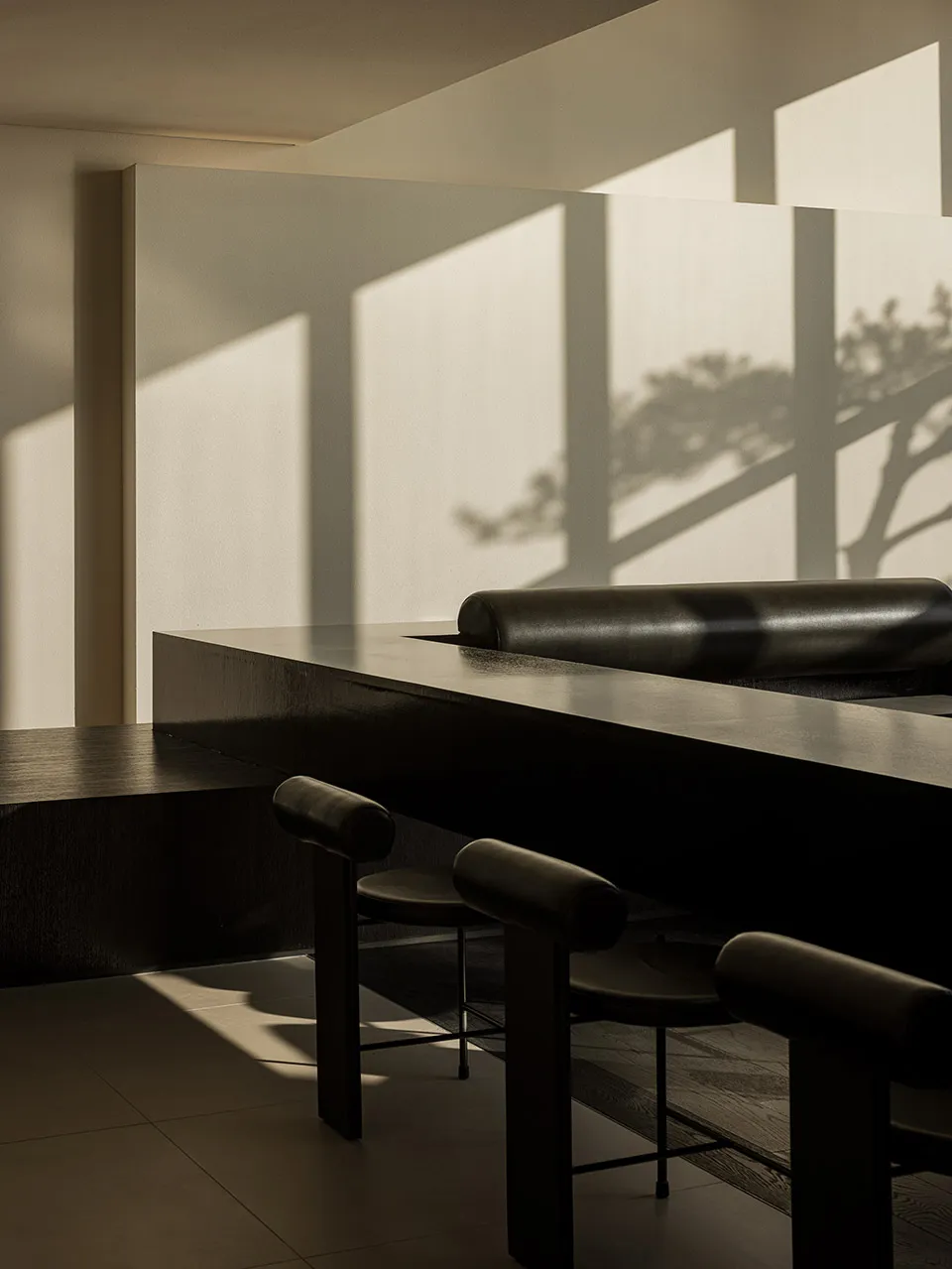 Modern minimalist restaurant bar with concrete surfaces and stools.