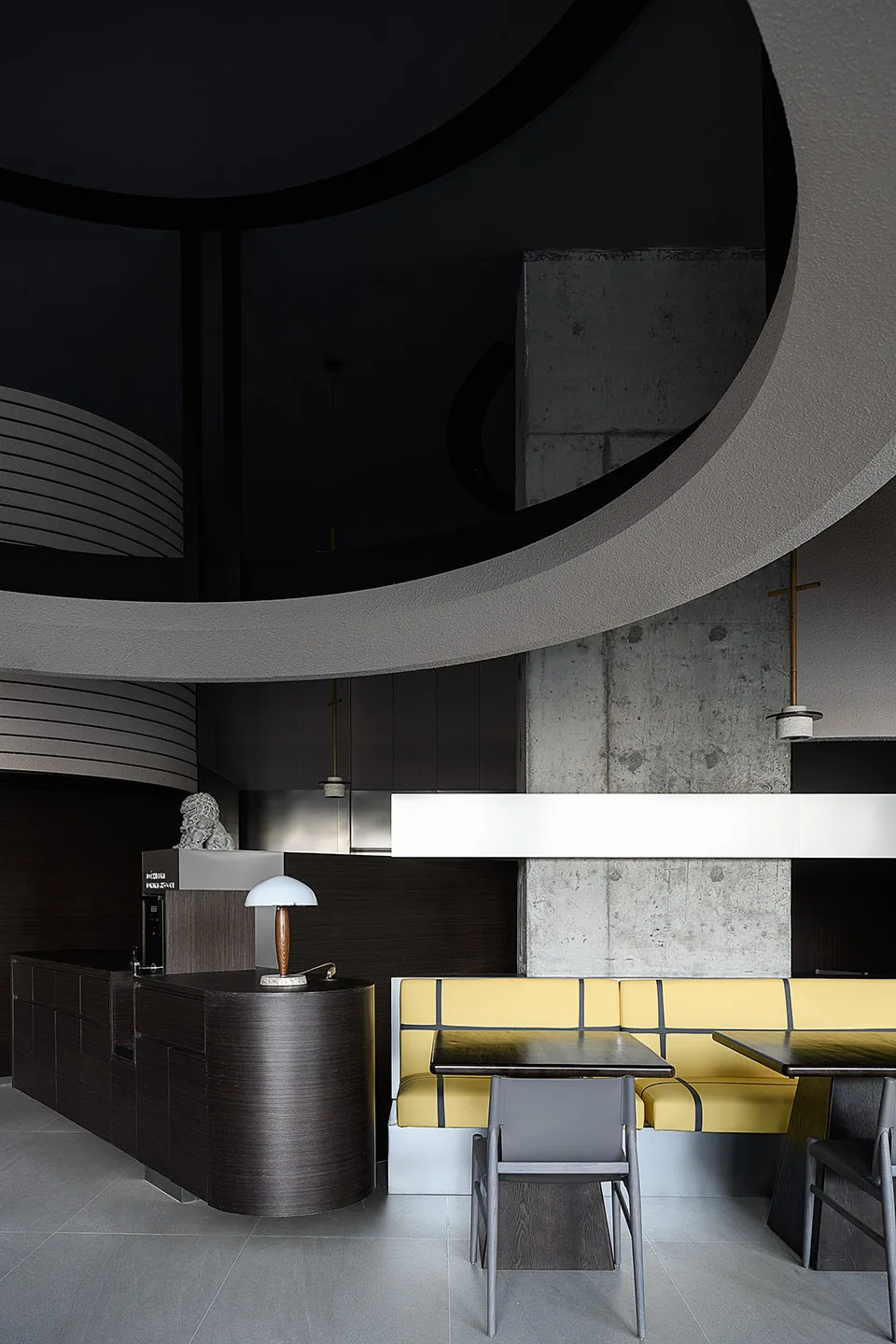 A modern restaurant interior featuring dark wood accents and concrete walls.