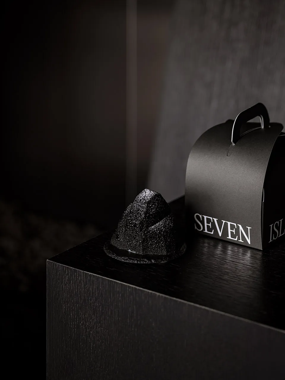 黑色極簡產品包裝,置於黑色表面上,印有「SEVEN ISLANDS」文字。