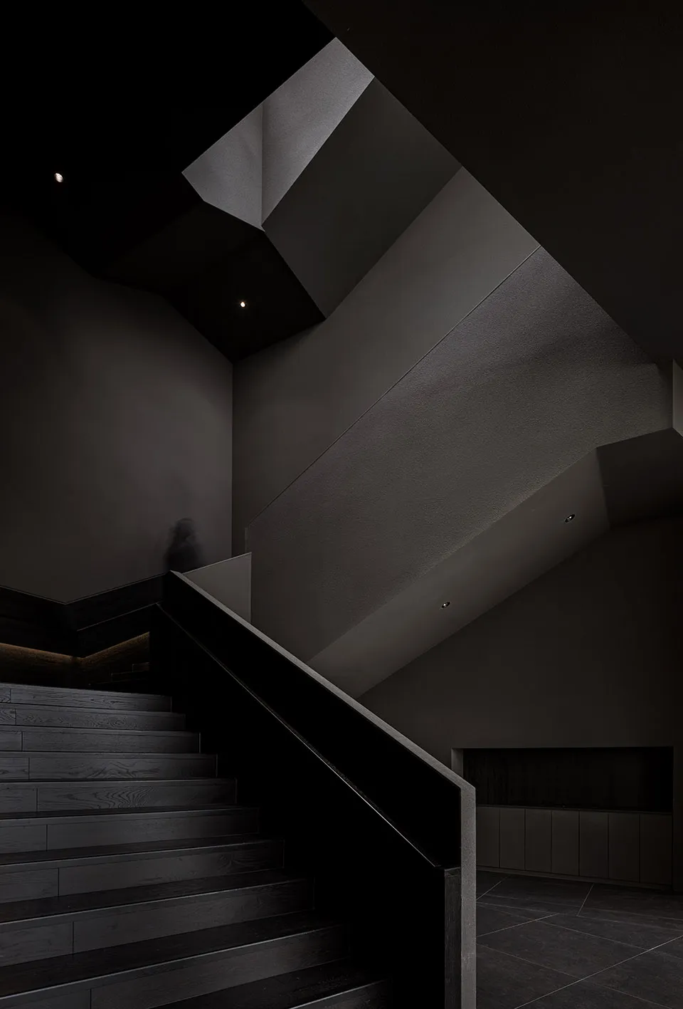 A modern interior space with black metal stairs and railings, featuring a minimalist design and dark walls.