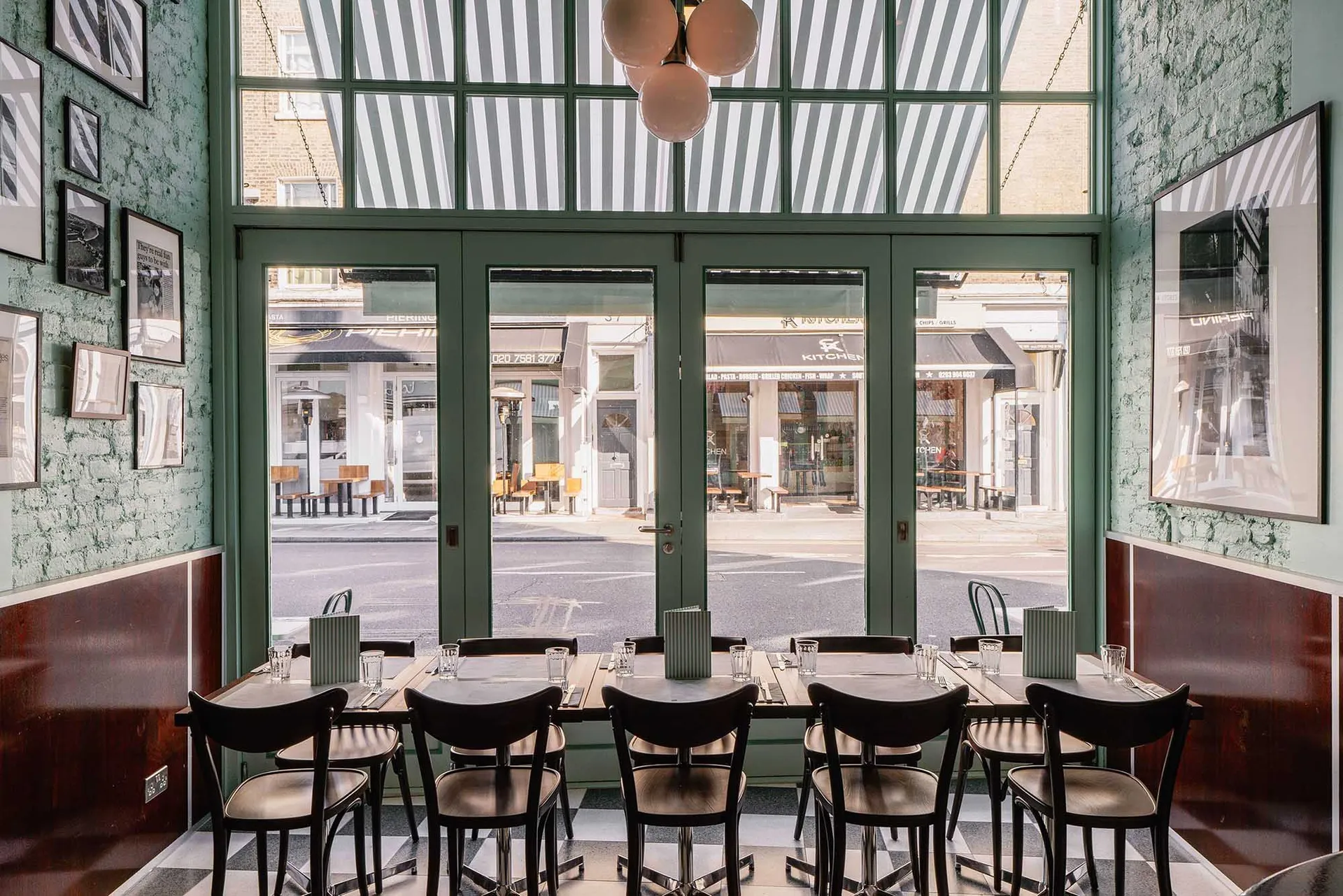 A modern restaurant interior with black chairs, large windows, and metal and glass features.