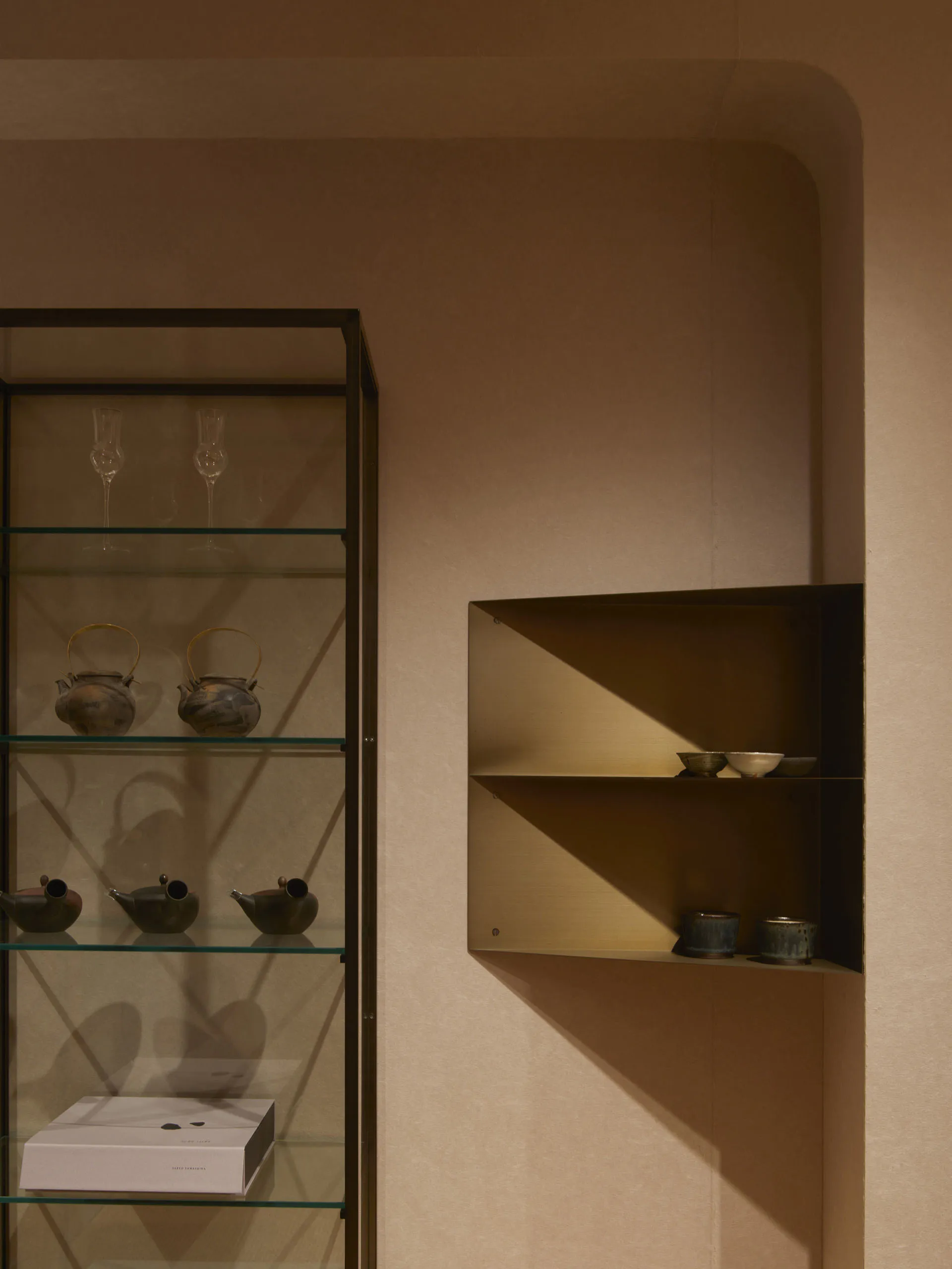 Glass shelves with various ceramic items in a neatly arranged display case.