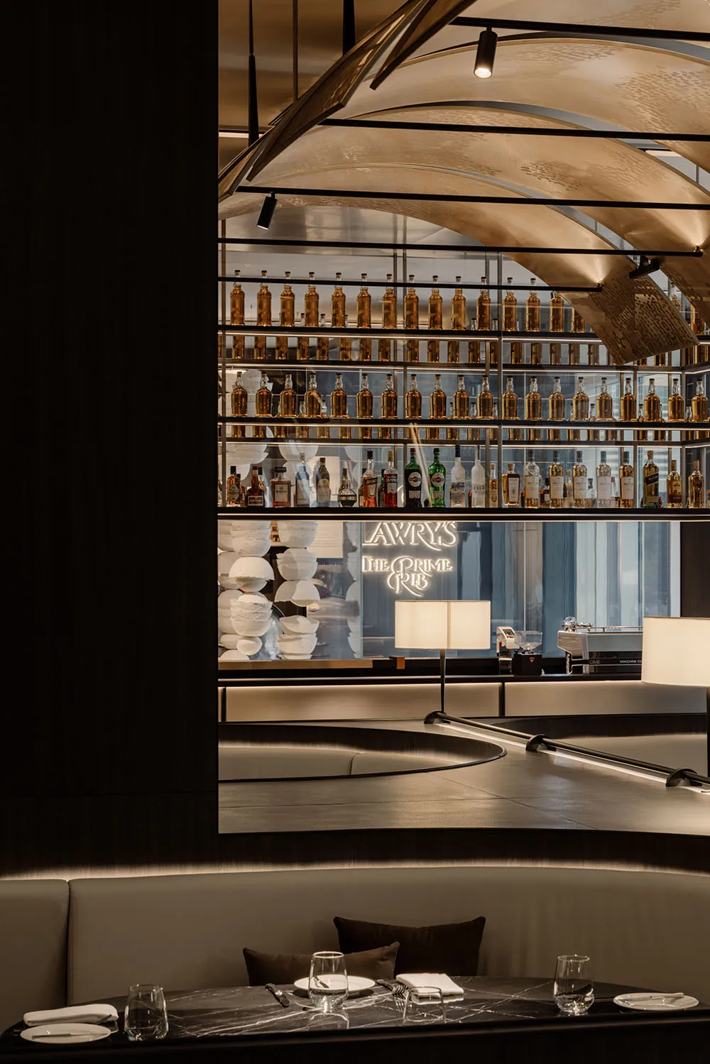 Industrial design restaurant interior with metal shelves, glass bottles, and marble tables.