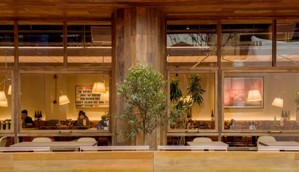 A rustic, industrial-themed restaurant interior with wooden accents and greenery.