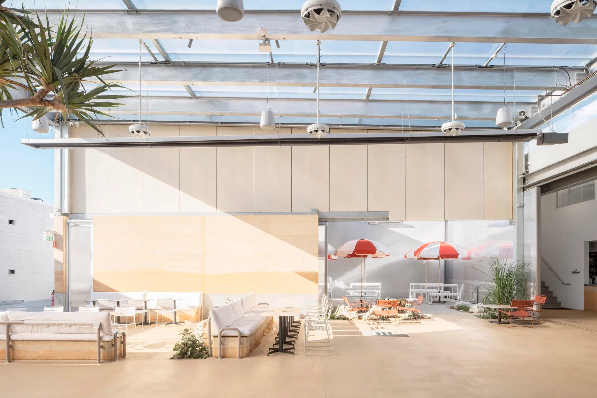Modern cafeteria seating area with concrete furniture and white umbrellas.