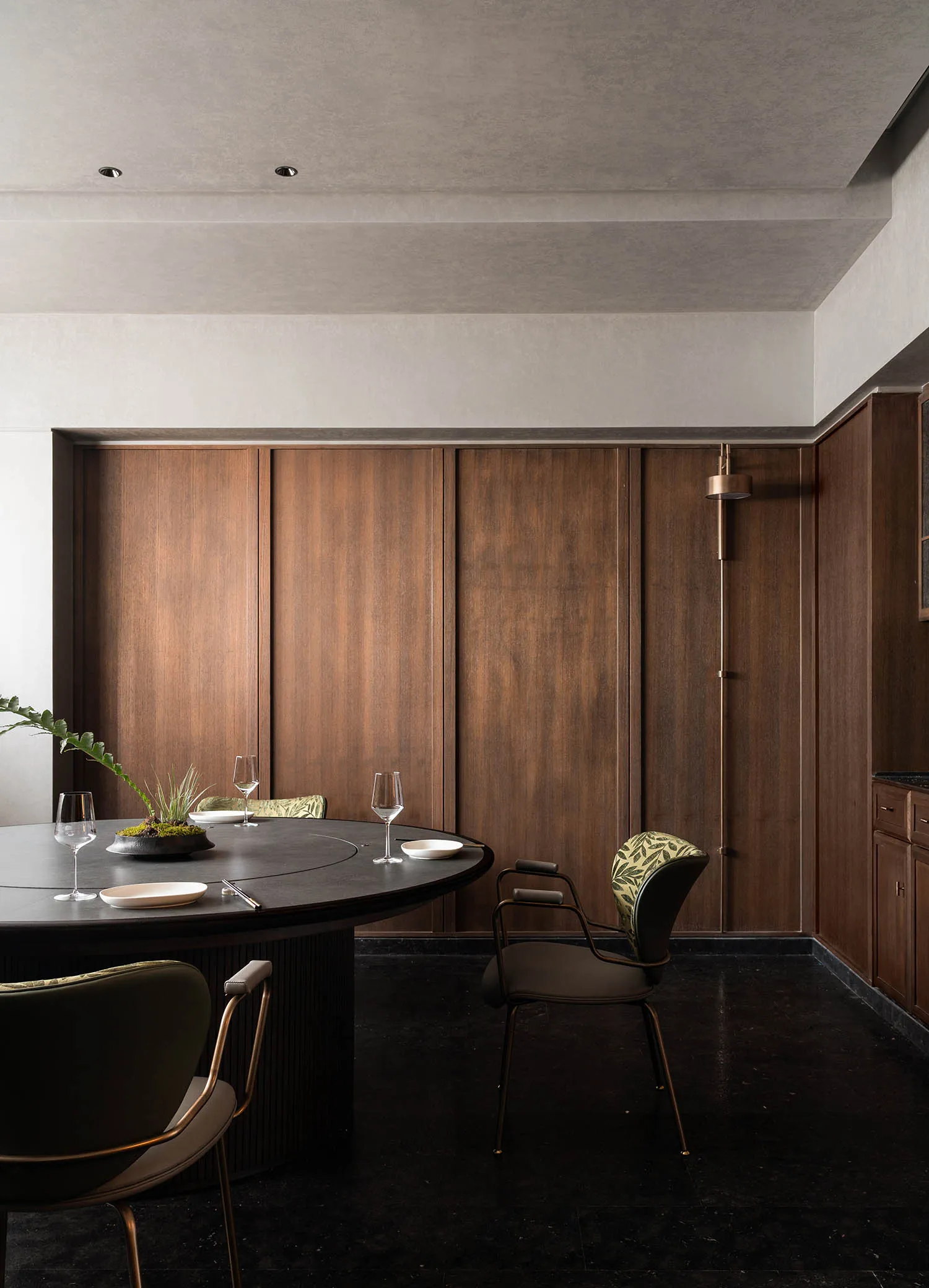 A modern dining area featuring a round wooden table with glassware and plates.