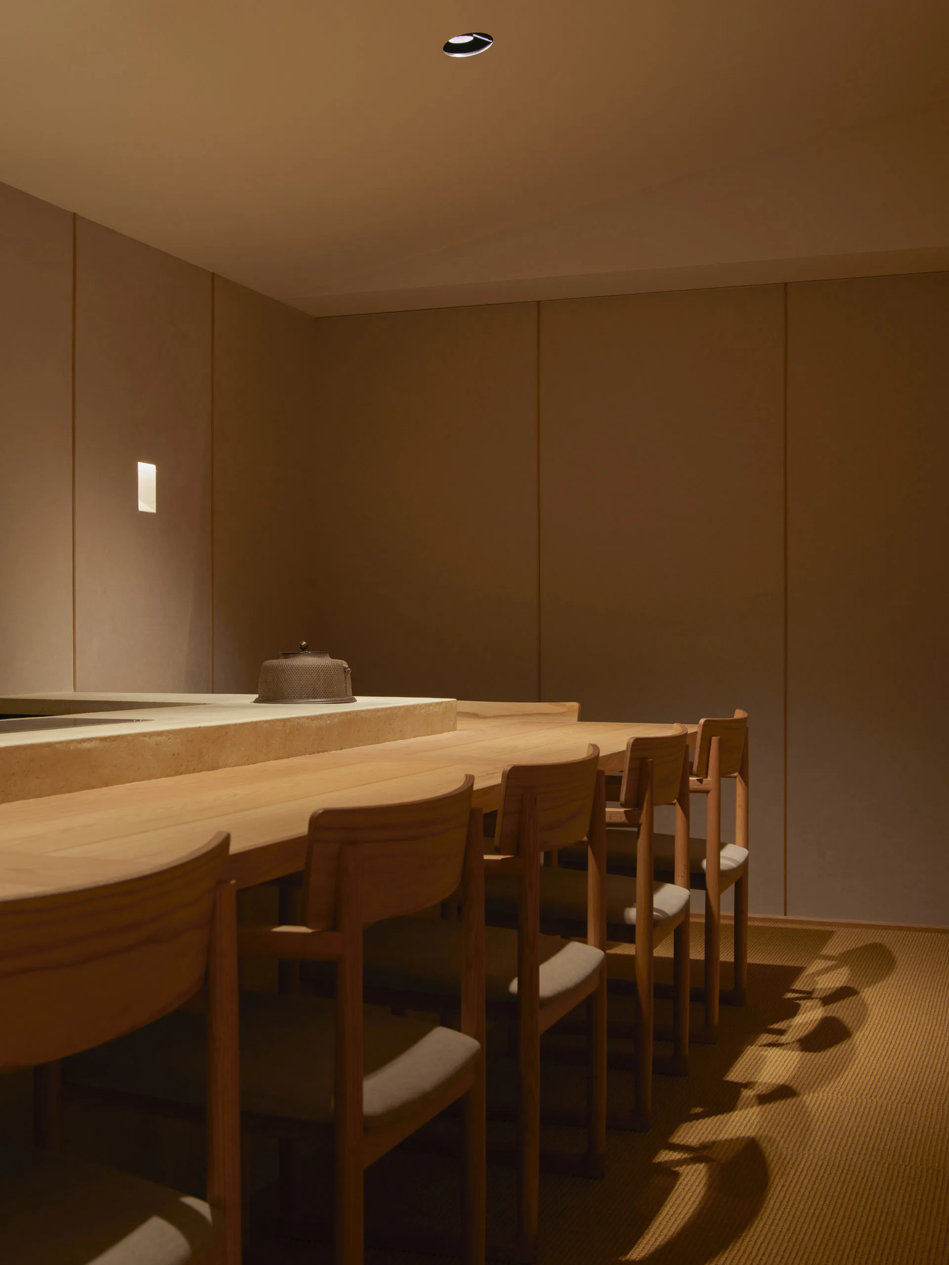 A minimalist restaurant bar featuring natural wood elements and soft lighting.