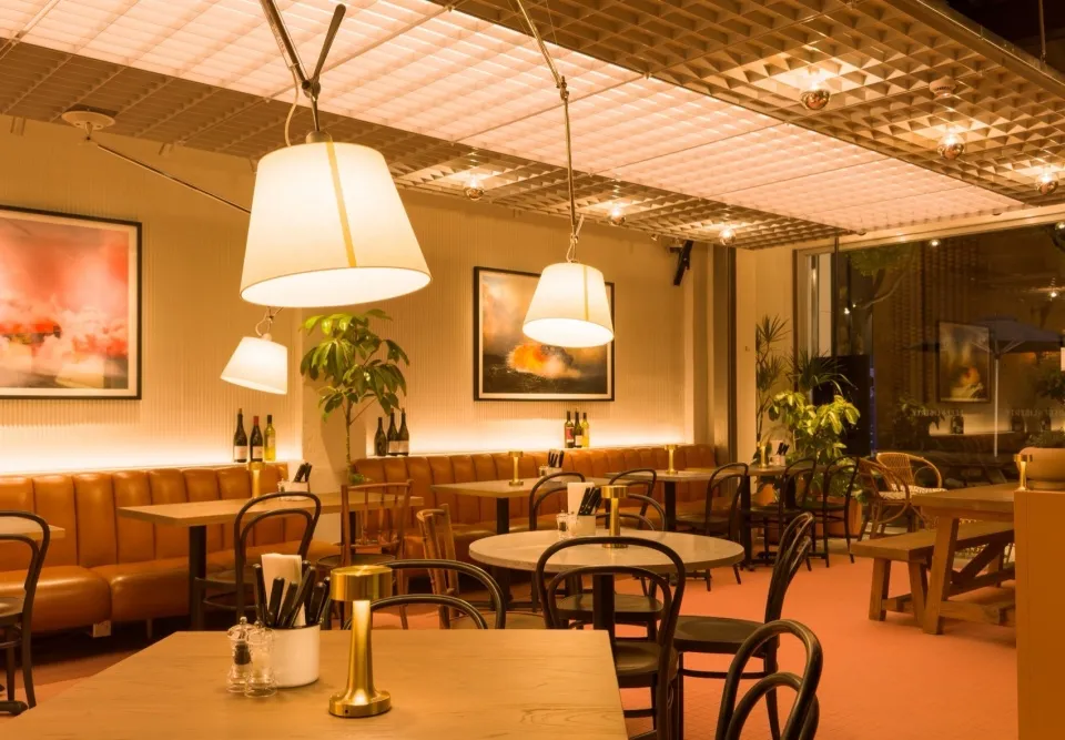 Modern cafe interior featuring wood tables, leather seating, and metal chairs.