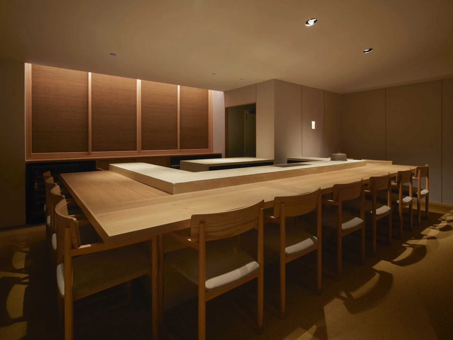 Modern minimalist restaurant interior with wooden furniture and concrete countertops.