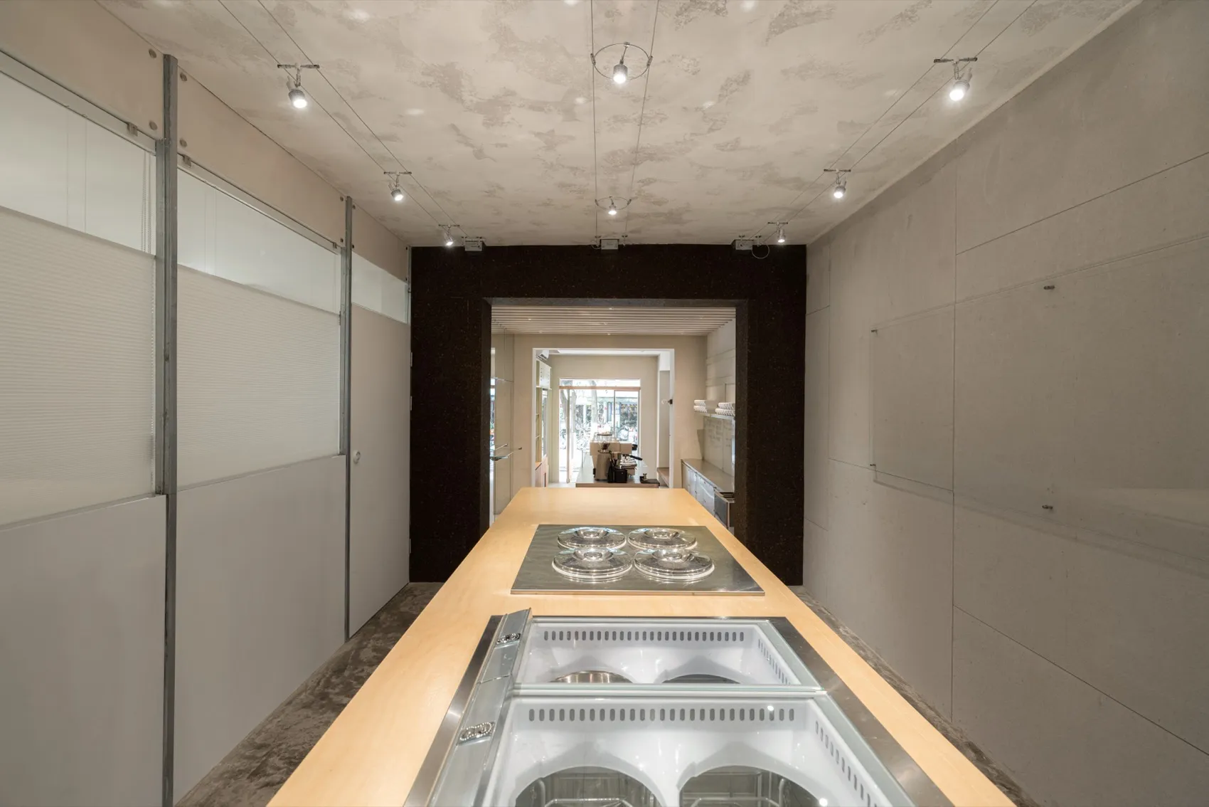 Modern retail environment with a metal countertop featuring espresso machines.
