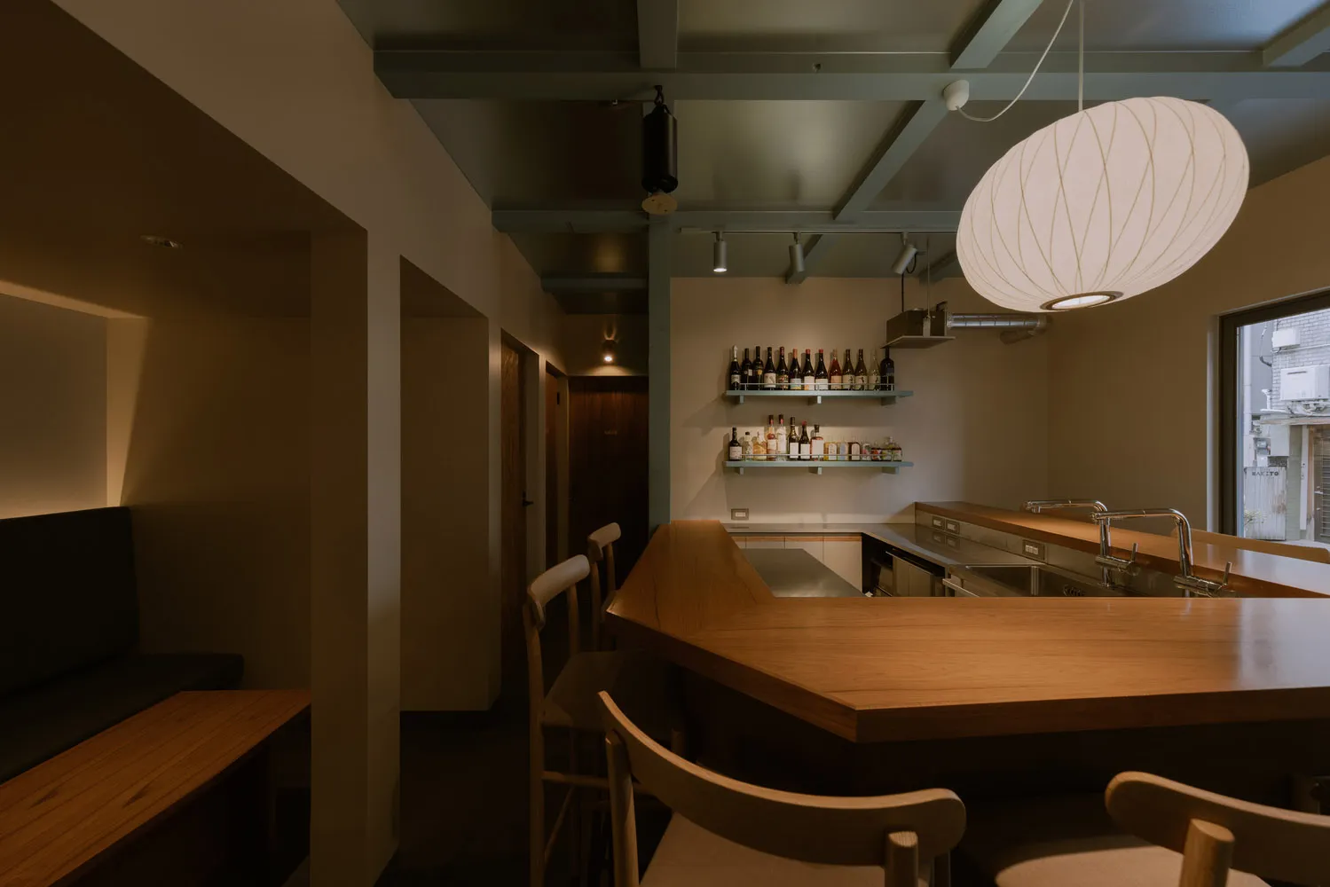 Industrial-style restaurant bar with wooden furniture and a variety of alcohol bottles displayed on shelves.