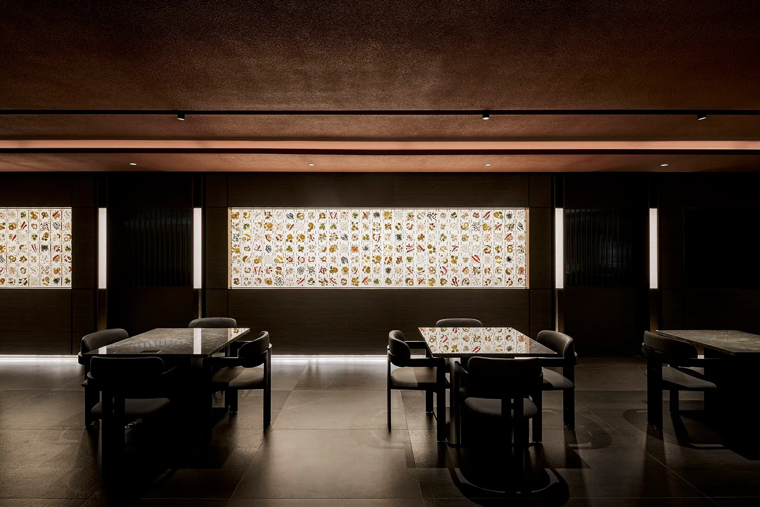 A modern restaurant interior with black materials and illuminated wall art.