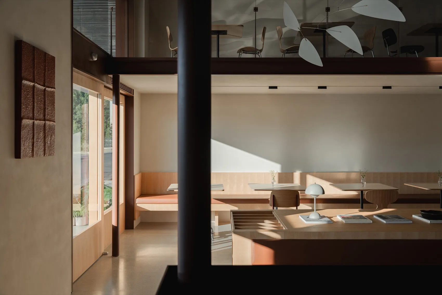 Modern cafe interior featuring wooden tables and chairs, neutral tones, and natural light.