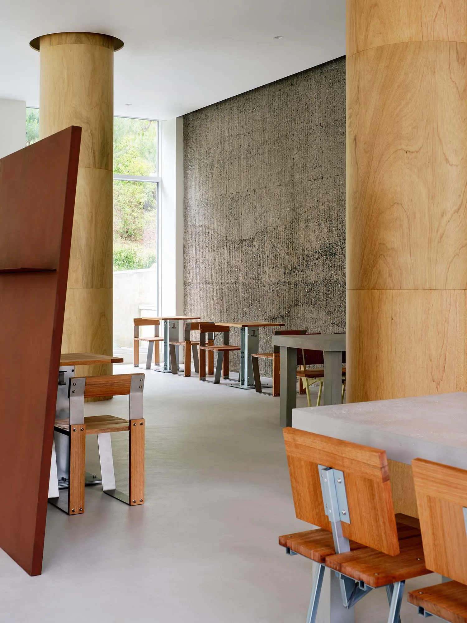 A modern industrial restaurant featuring wooden tables and concrete floor and walls.