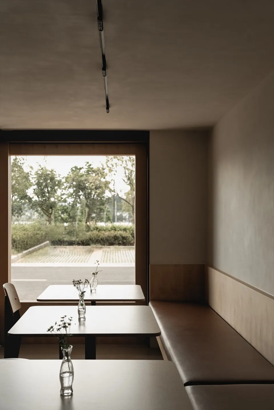 A minimalist restaurant interior with modern elements and a view of greenery outside.