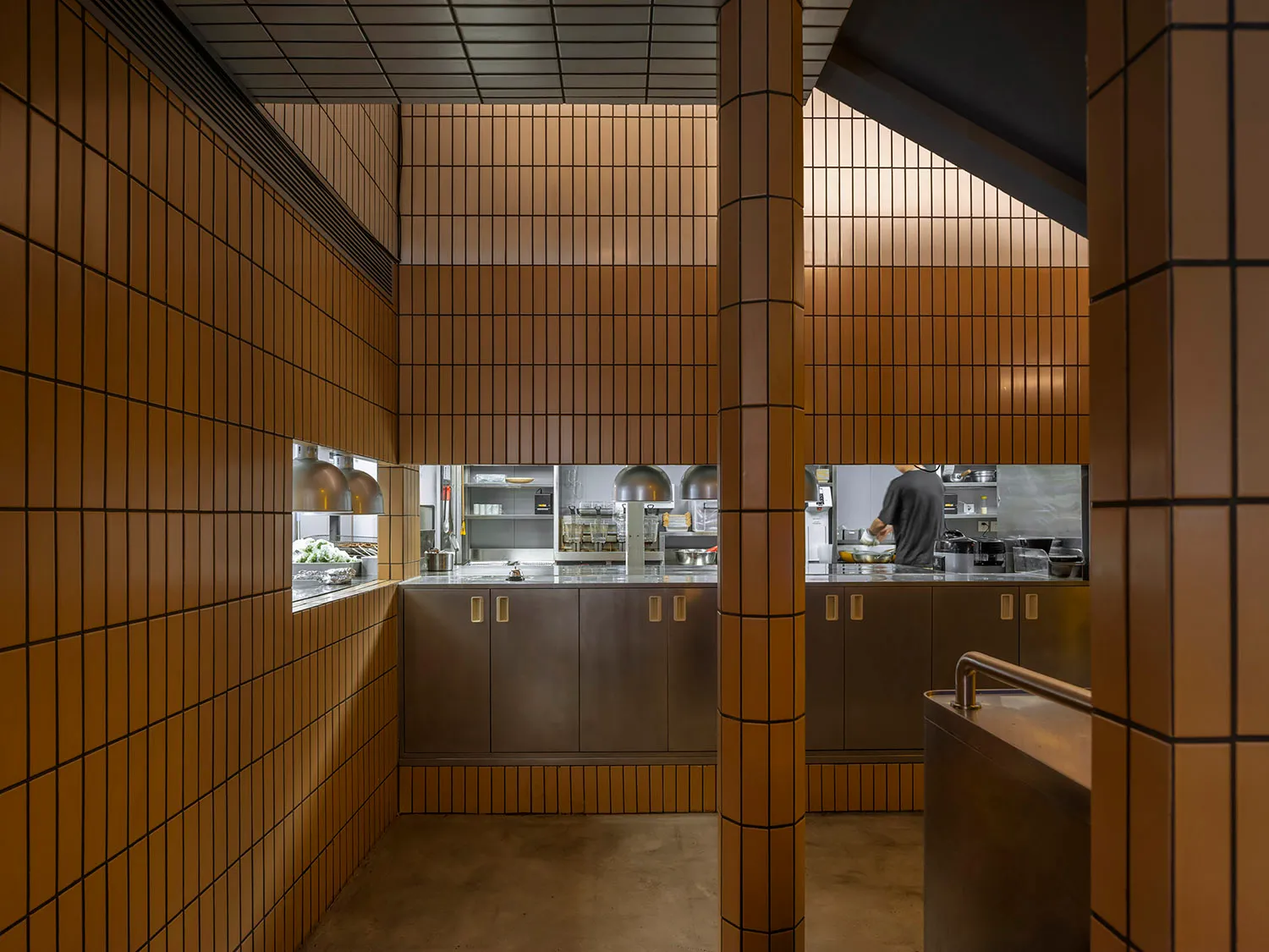 A spacious, industrial-style restaurant kitchen with concrete walls, metal countertops, and a minimalist design.