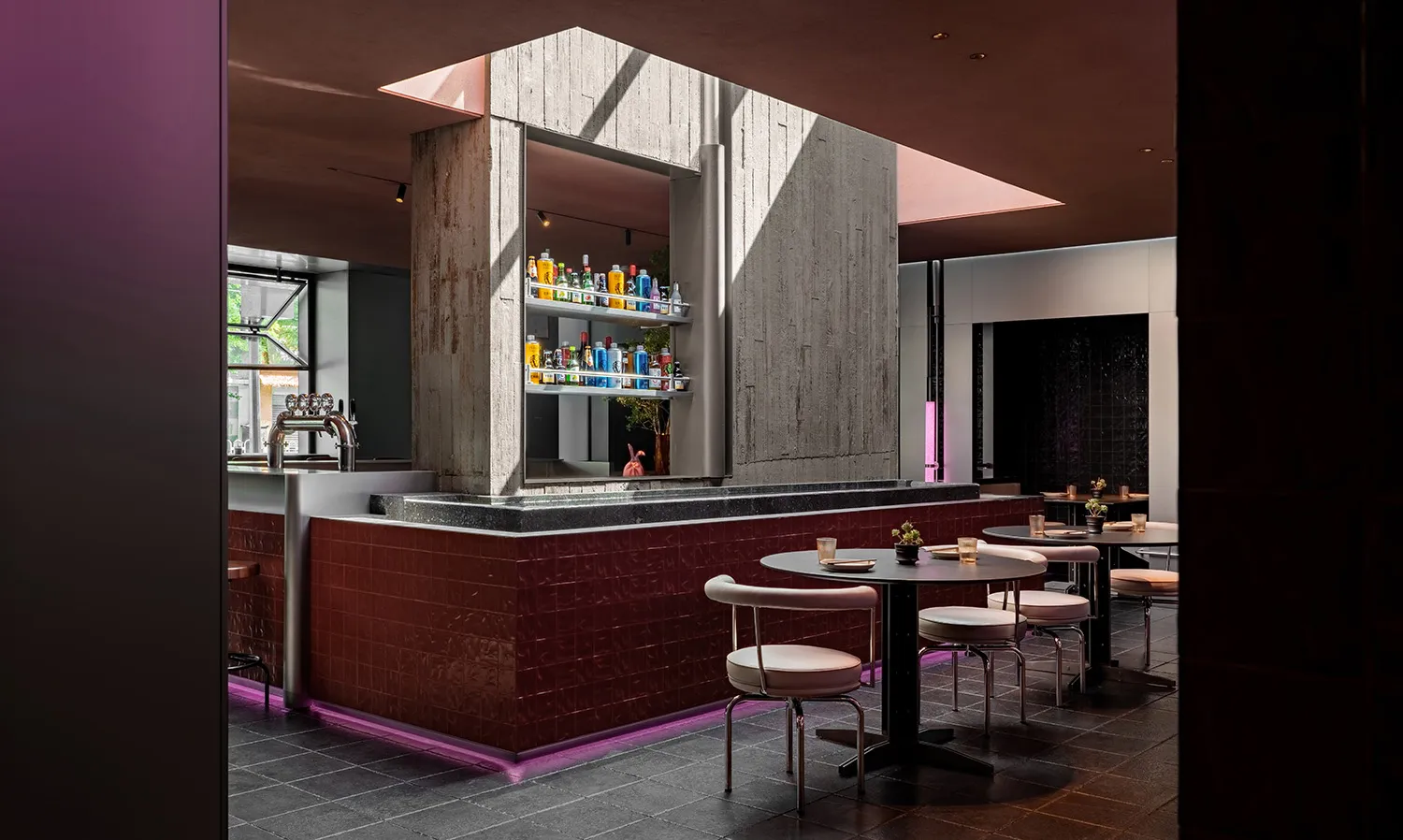 Modern cafe-bar interior with concrete walls and tables surrounded by chairs.
