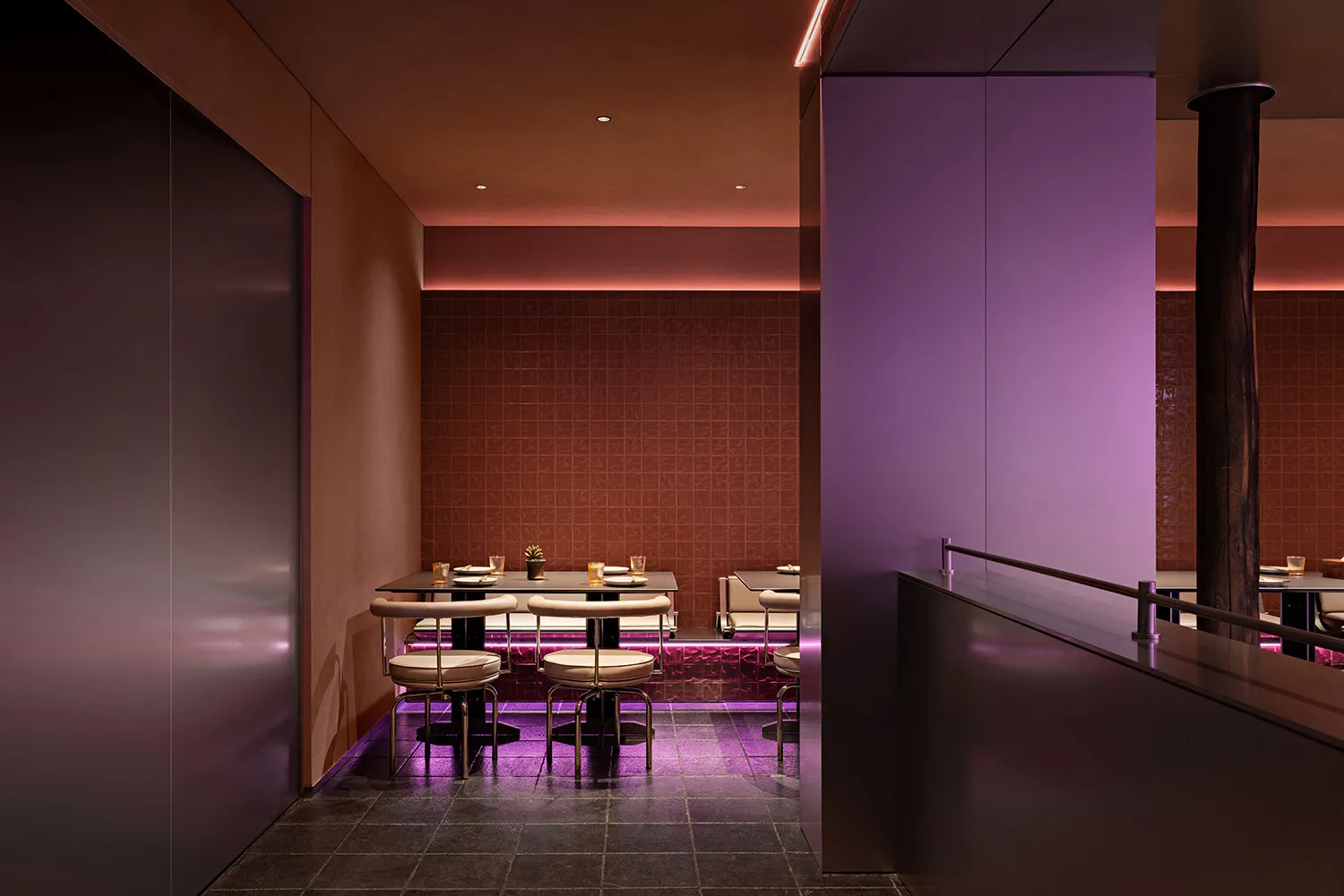 An interior view of a modern restaurant with purple lighting and metallic accents.