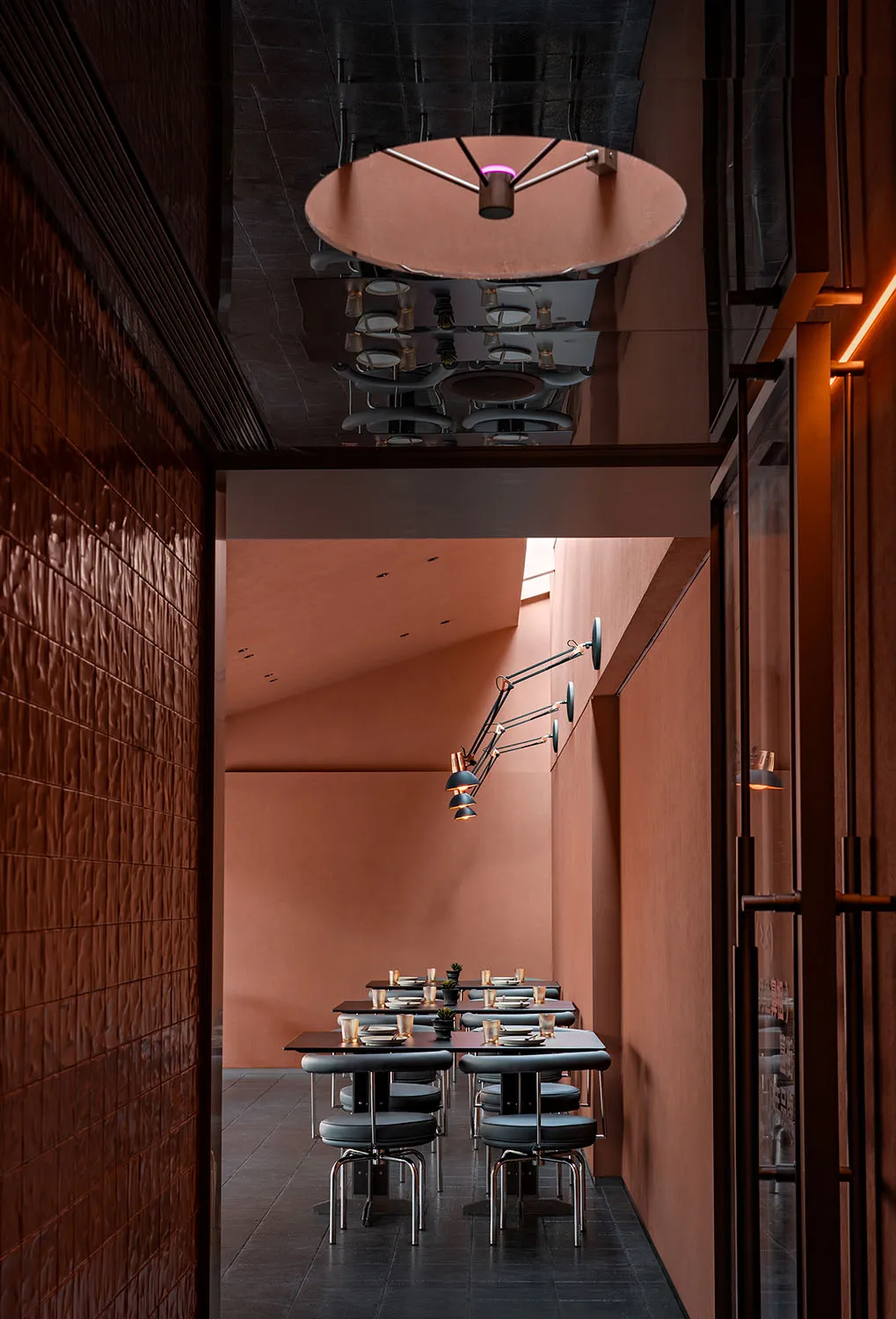 A modern restaurant dining room with metallic textured walls and black, industrial-style chairs.