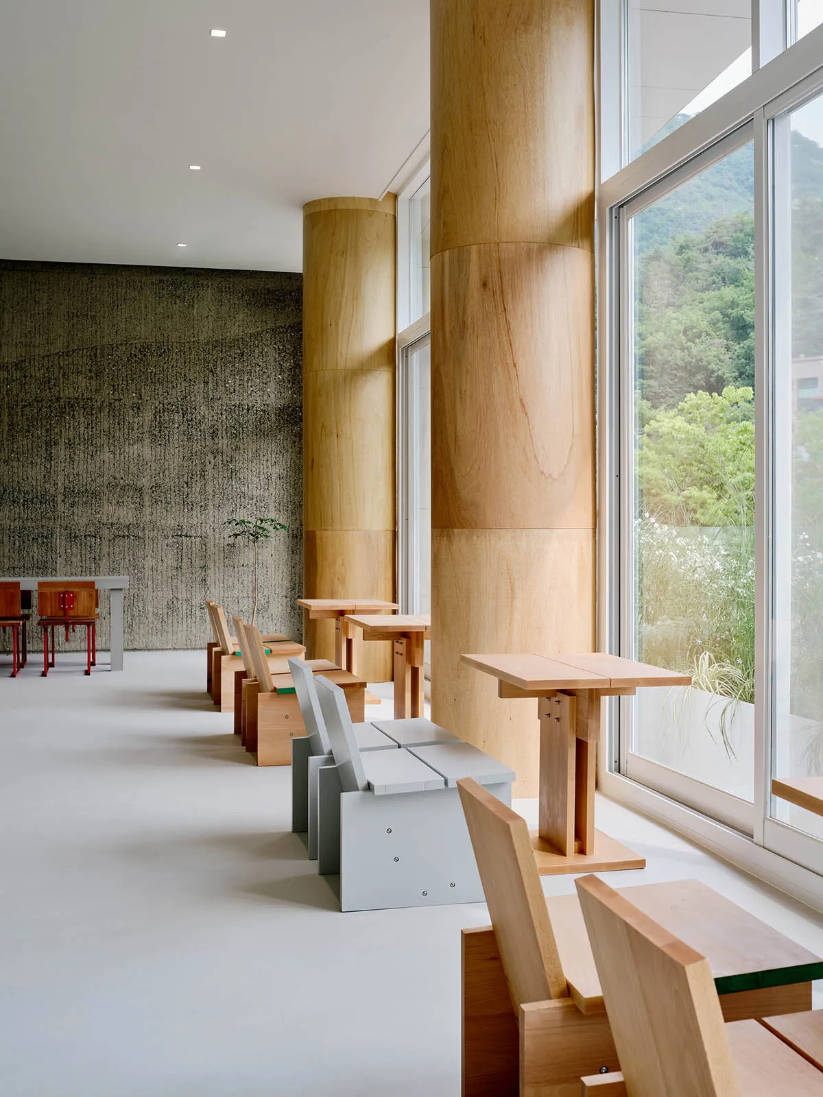 Modern restaurant interior with minimalist design featuring wooden tables and chairs.