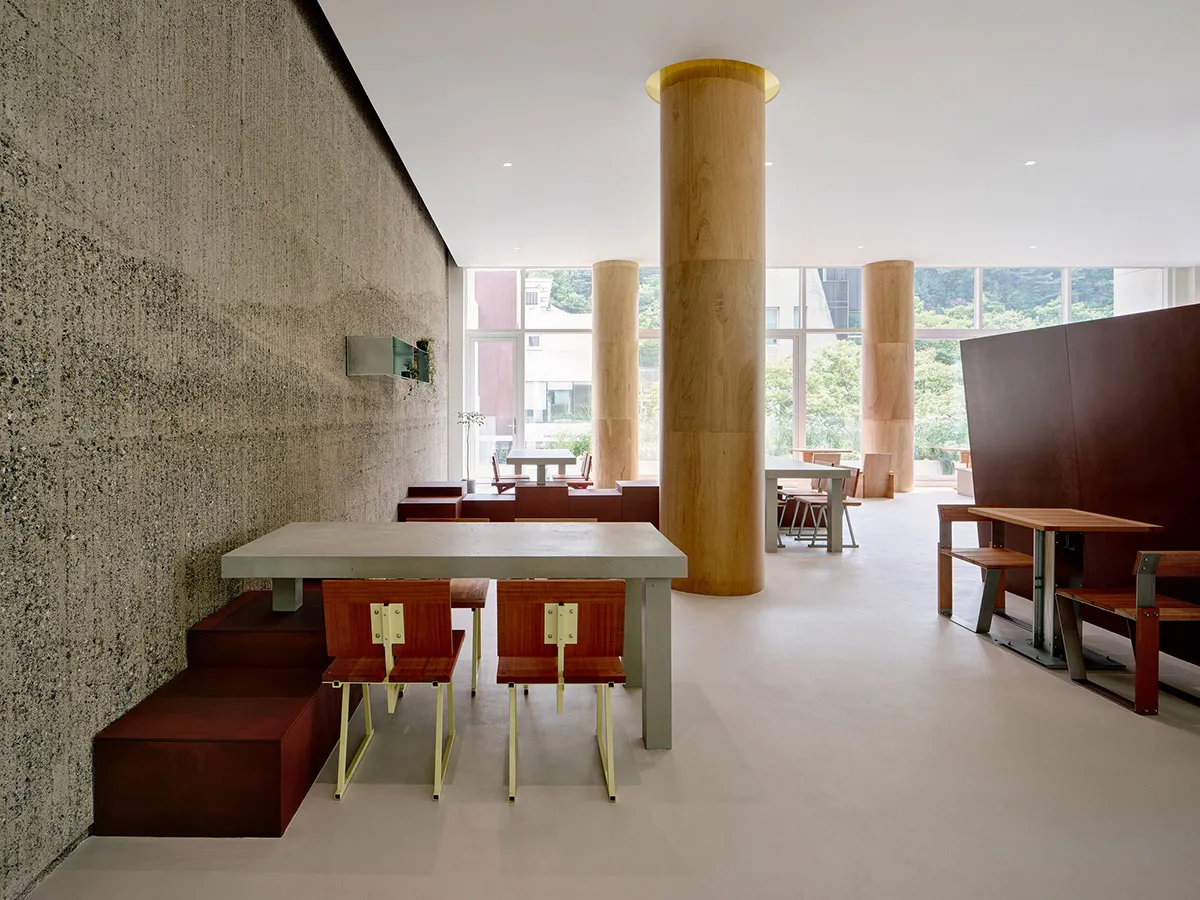 A stylish modern coffee shop with concrete walls, wooden tables, and steel furniture.