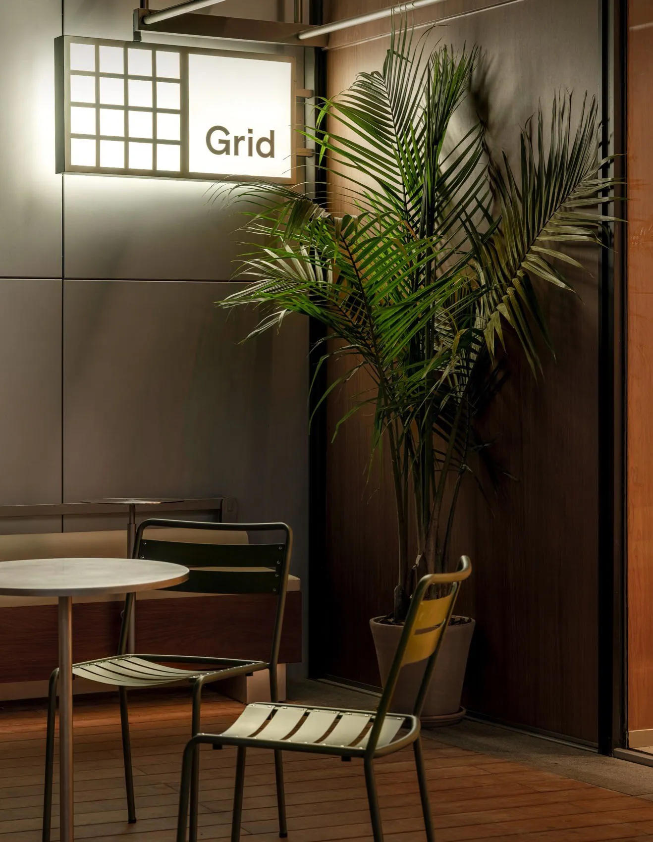 A modern cafe interior featuring metallic accents and a tropical plant.