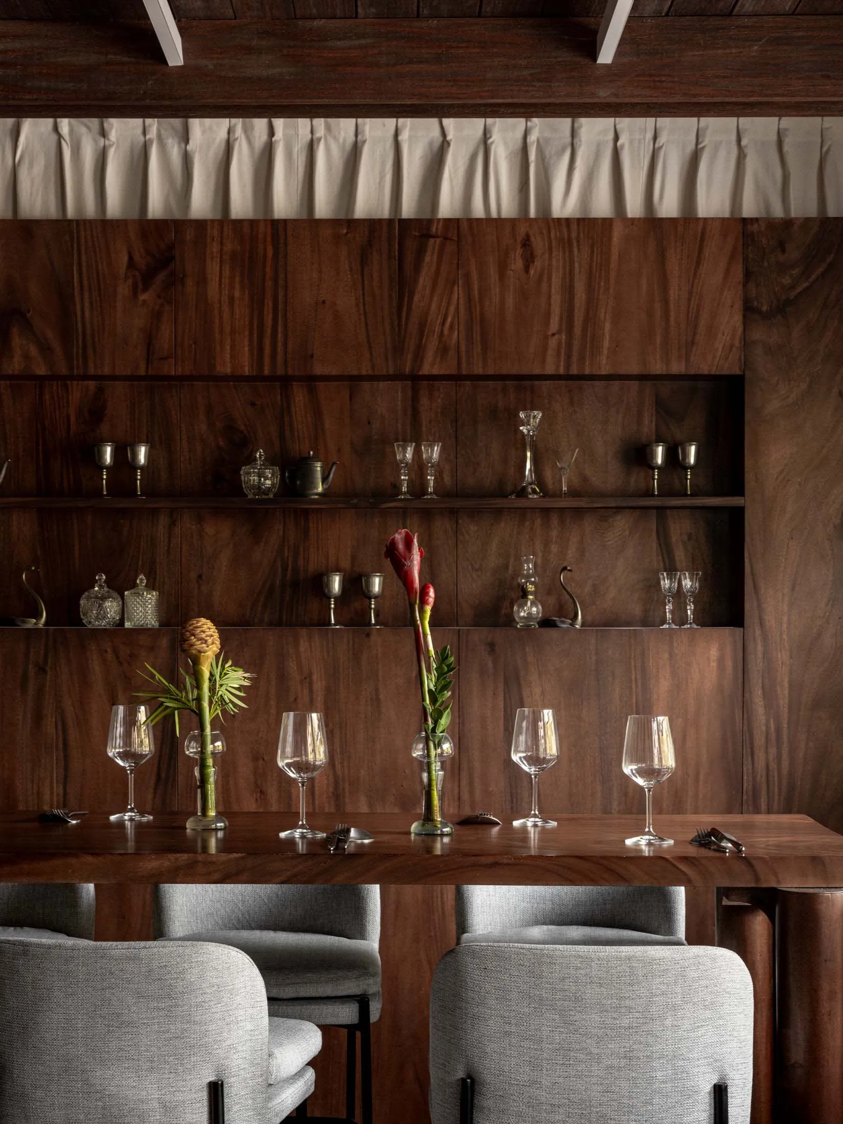 A modern industrial-style restaurant interior with wooden walls, shelves, and a table, and fabric-covered seating.