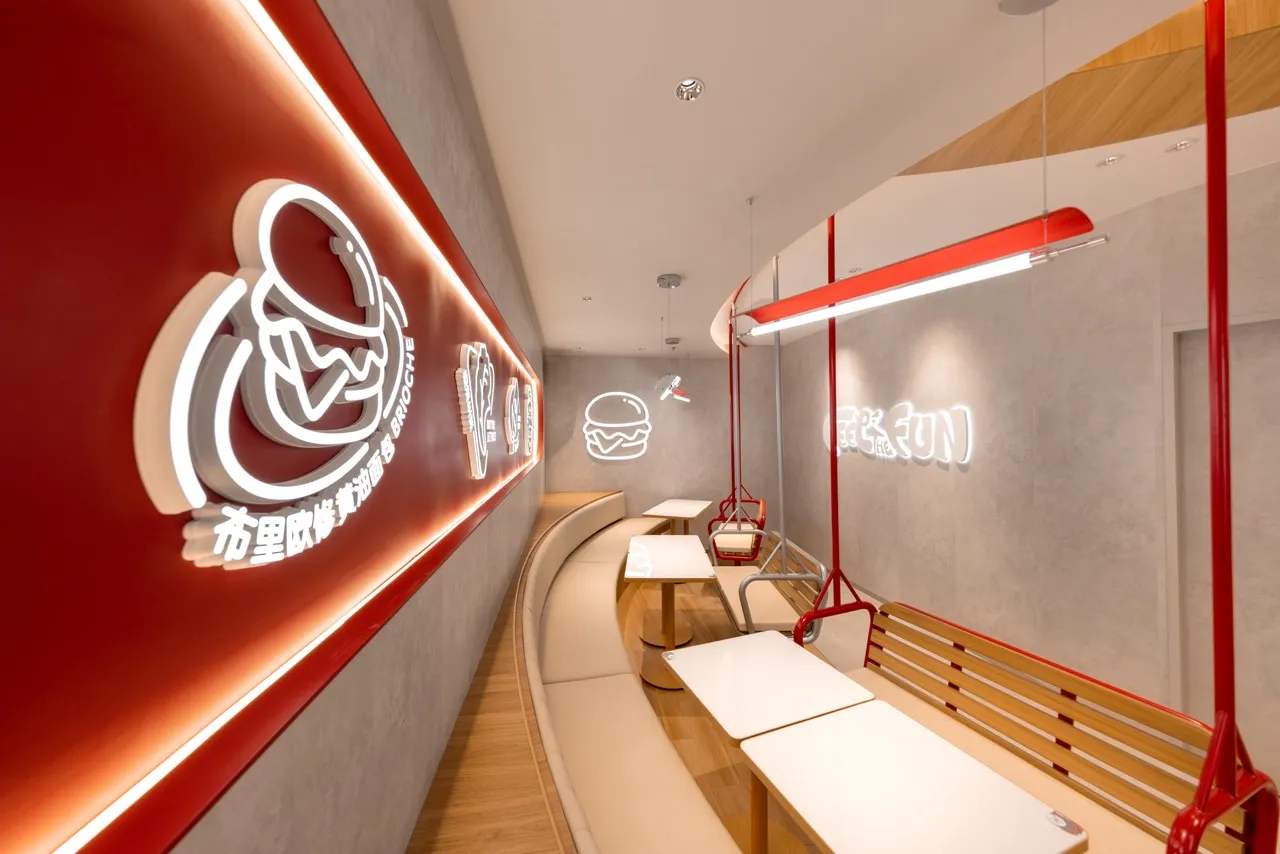 A minimalist restaurant interior with concrete walls, wooden seating, and neon lighting.