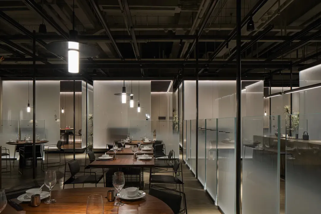 Modern industrial restaurant interior with glass walls and minimalist design.